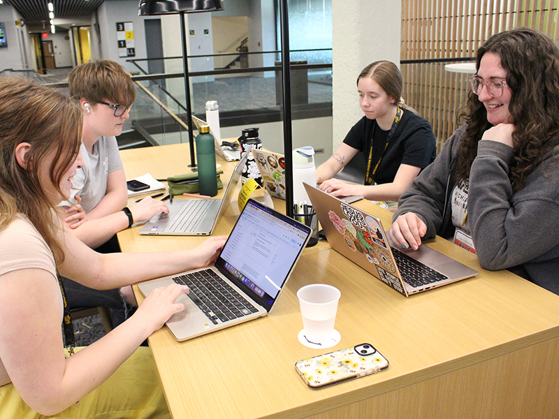 Four students seated at a table study together.