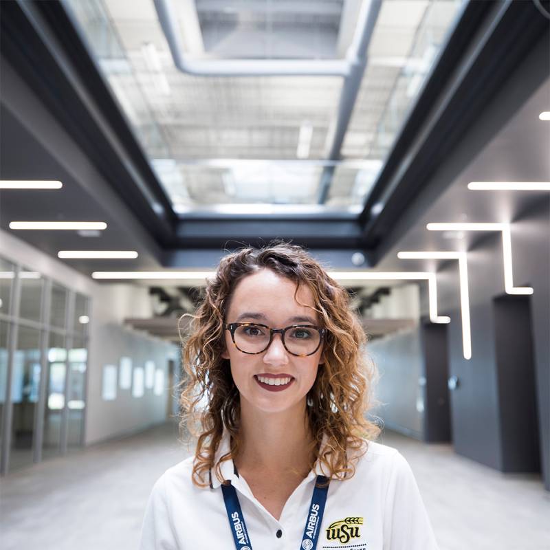 A young woman stands in a lab coat