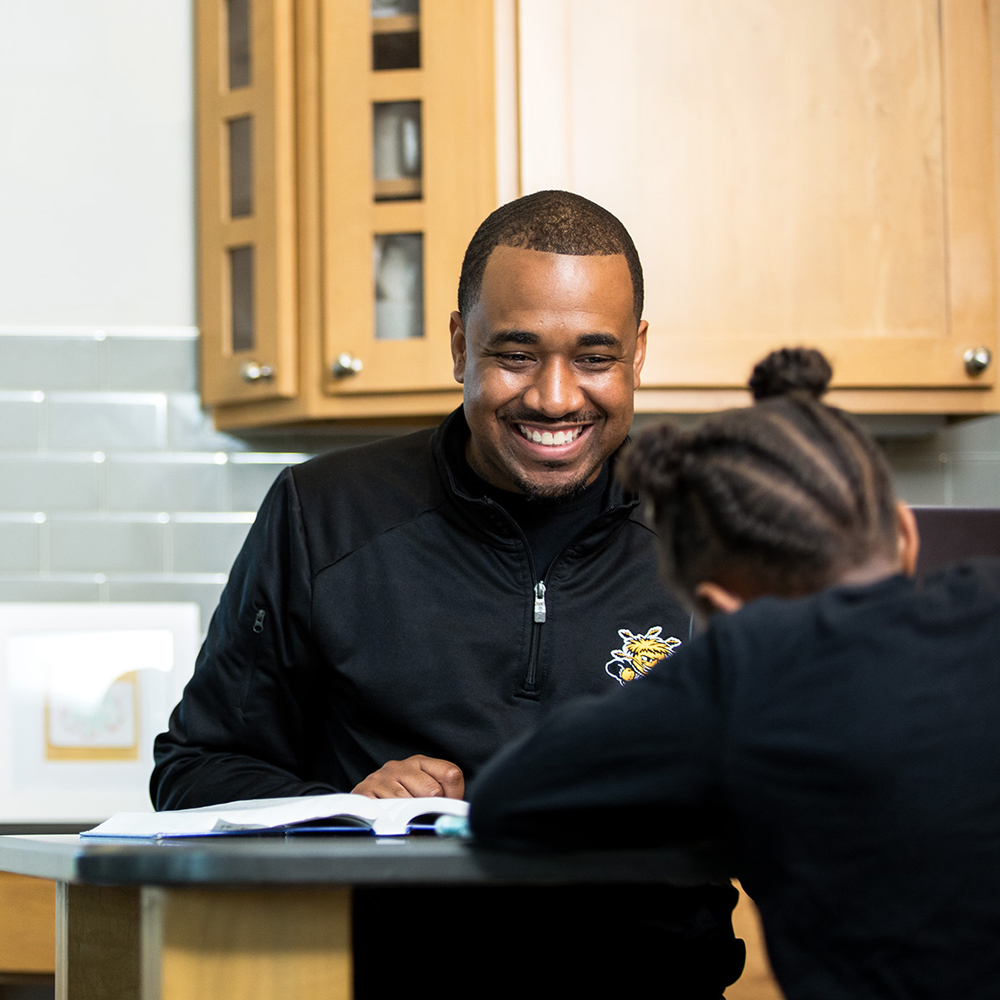 Returning adult online student studying at home with his daughter.