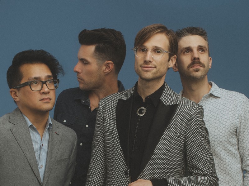 Band members of saint motel standing next to a piano