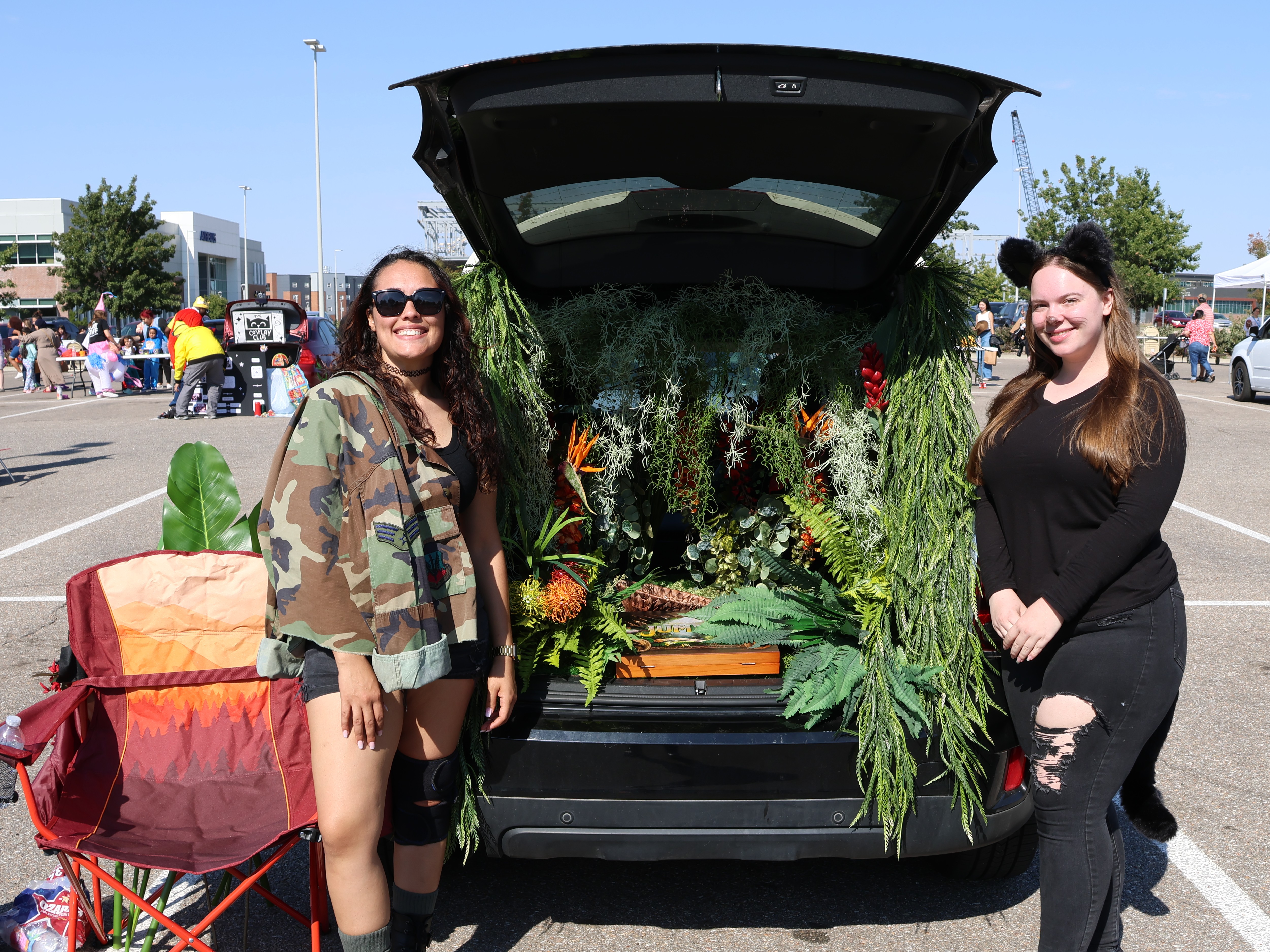 Two members of a student organization standing in front of a jungle themed decorated car.