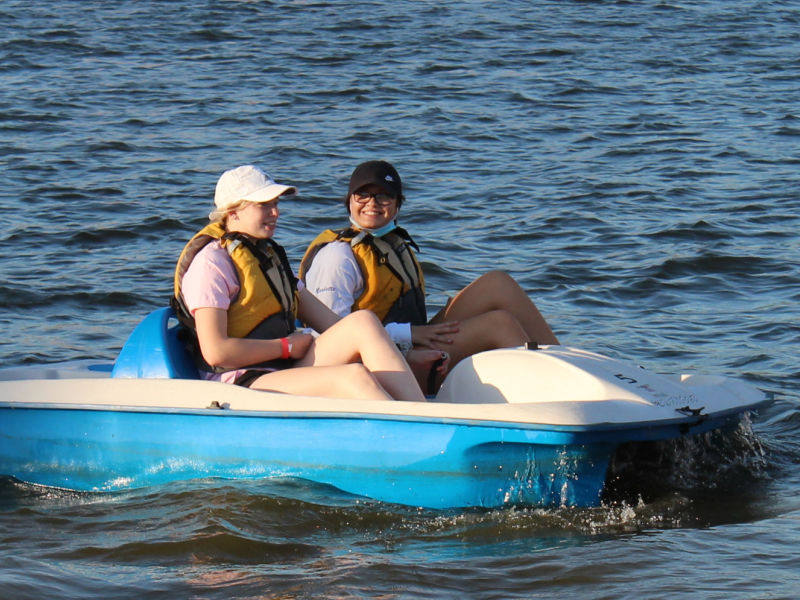 Two students riding in a paddle boat on the river
