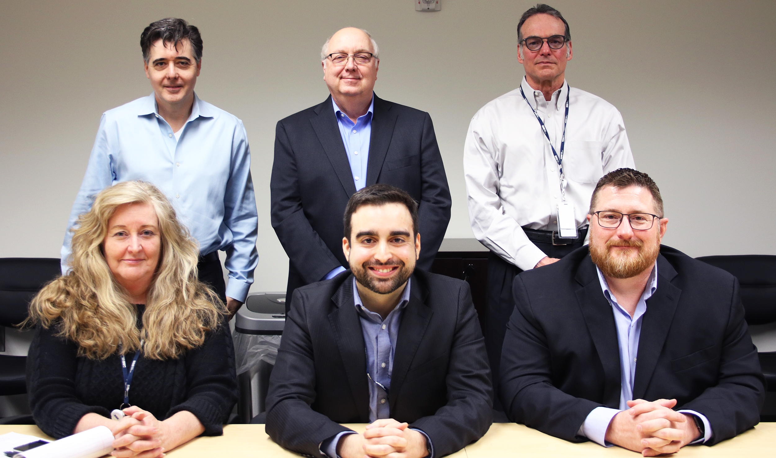3S team sitting and standing together for a picture at the conference table.