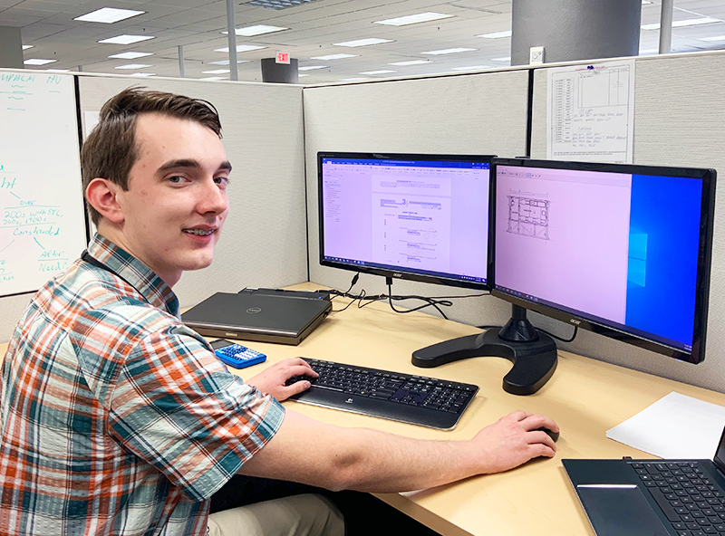 Corey Hubbard sitting in front of his moniters in his cubicle at 3S.