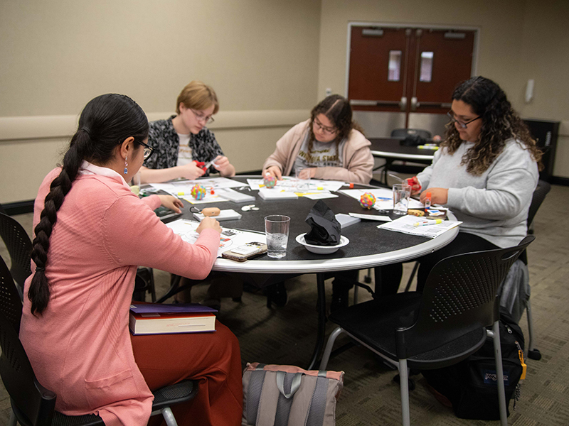 Image of Wichita State students gathered around a table creating design your life diagrams.
