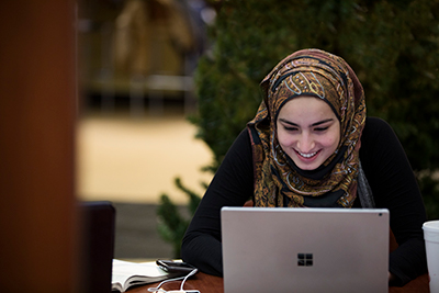 Female student on her laptop smiling. 