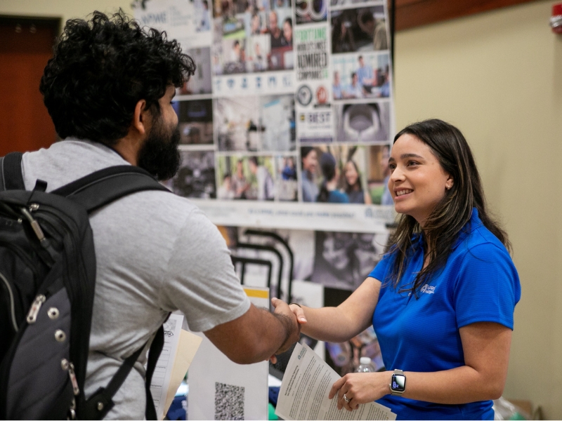 Student shaking hands with employer at a career fair.