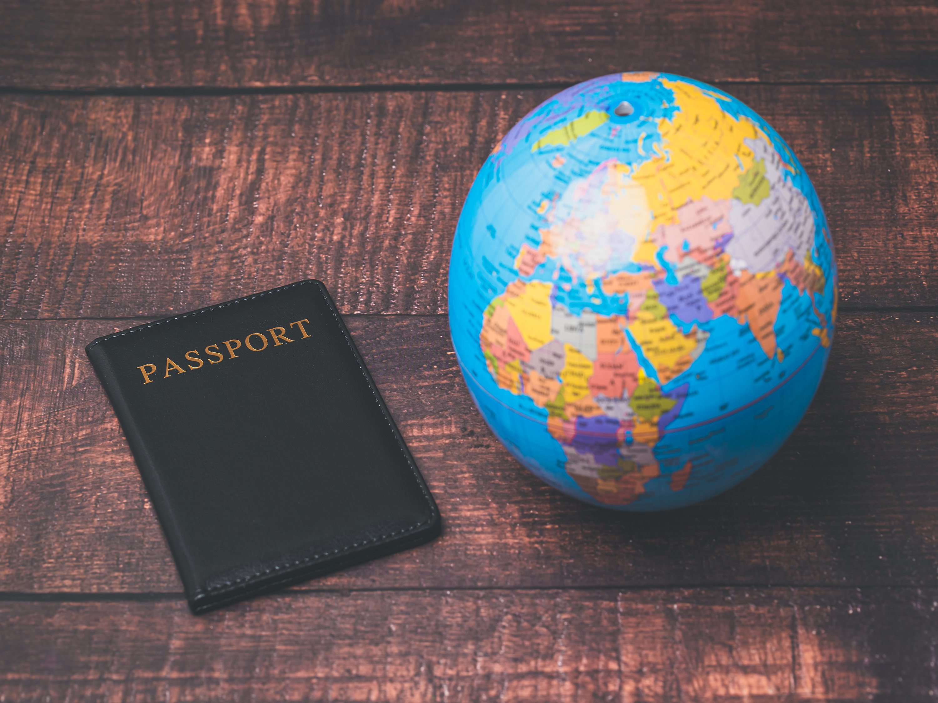 Passport next to a globe on a wooden surface