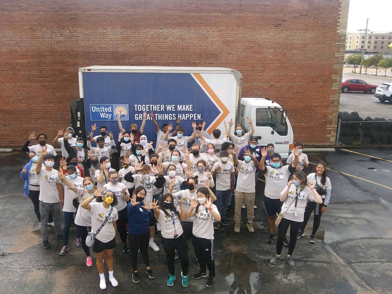 A large group of students smiling for the camera in front of a United Way truck