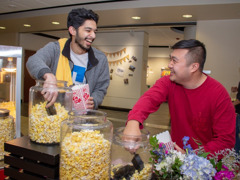 Two students grabbing popcorn at an event
