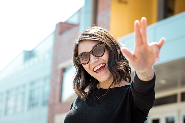 Student in front of the RSC with the shocker hand sign