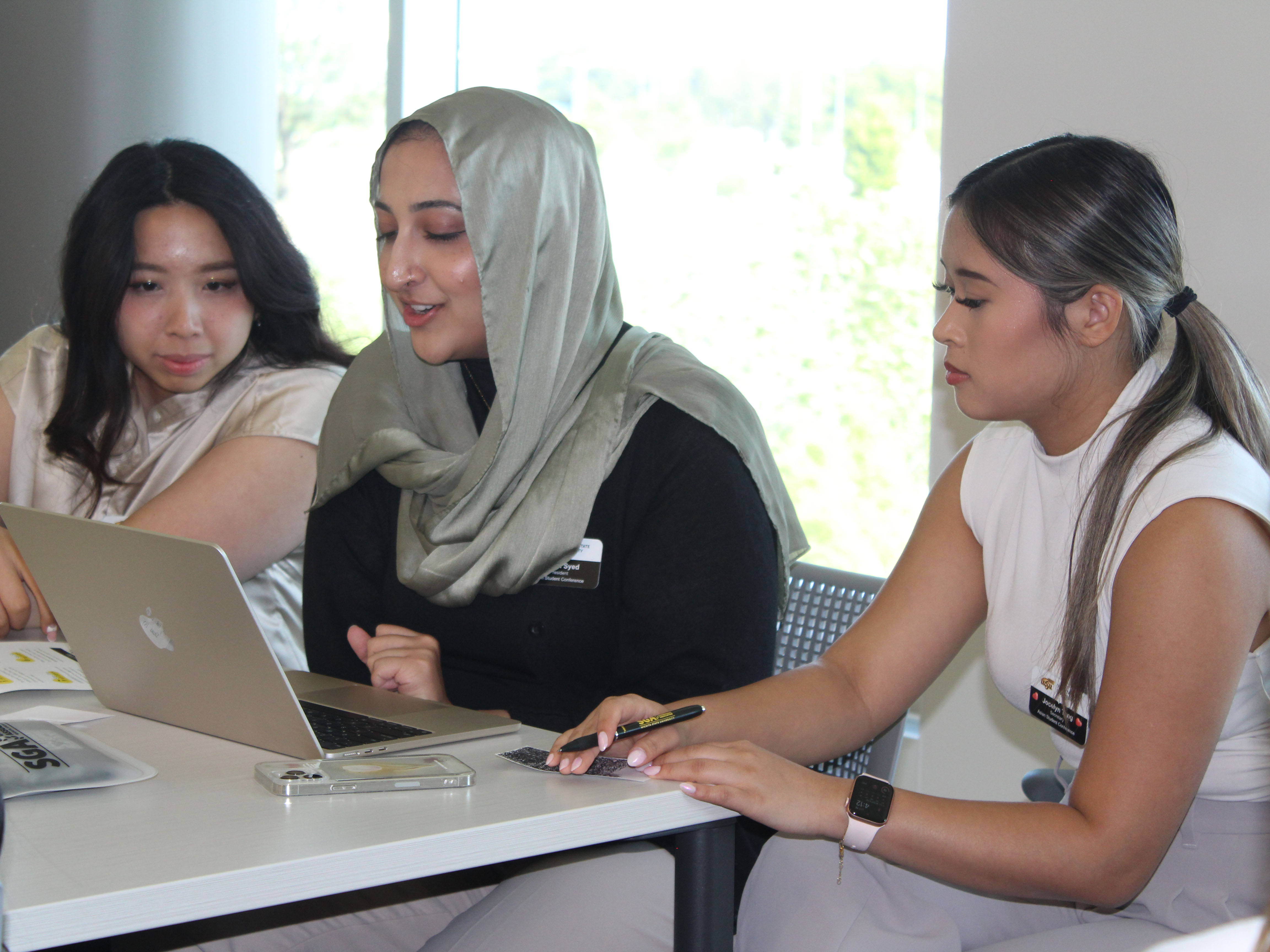 students surrounding a laptop as they work together during a retreat exercise