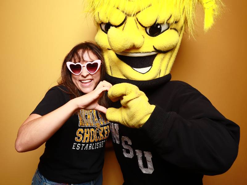 Student making a heart shape hand with WuShock during Wu's Birthday Bash