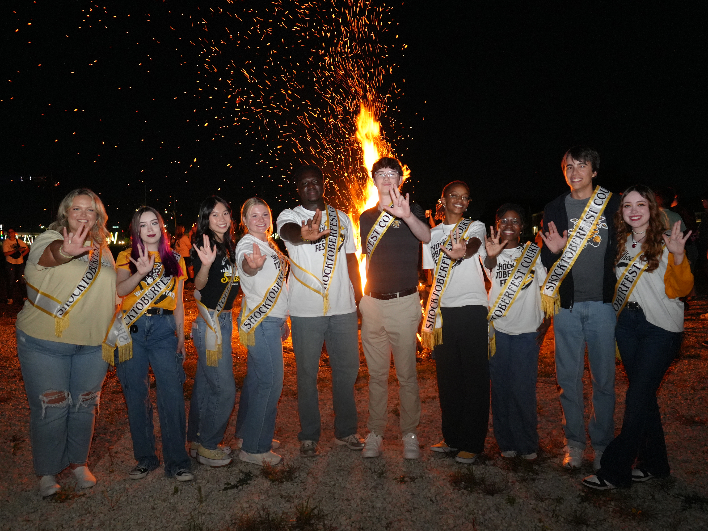 Shocktoberfest royalty students posing for the camera in front of a bonfire.