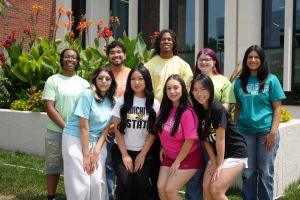 Students huddle together in front of flowers