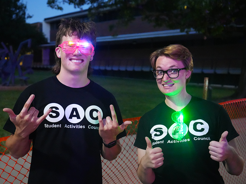 Two students posing for the camera with glow sunglasses during the SAC Foam Drop Dance Party.