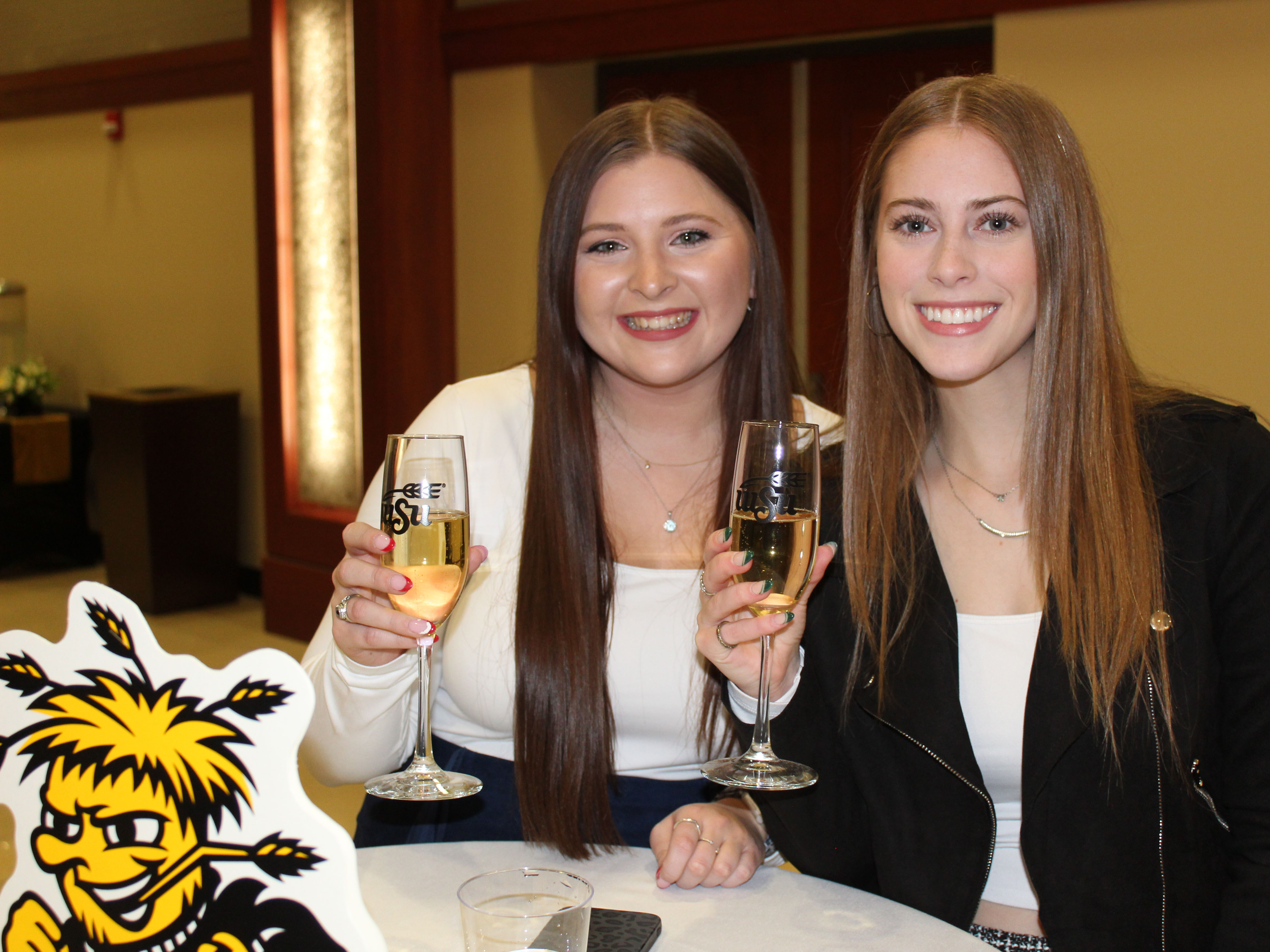 Two students smiling for the camera holding up their champagne flute