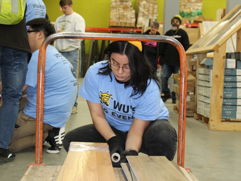 Student moving flooring at Give Warehouse for Wu's Big Event
