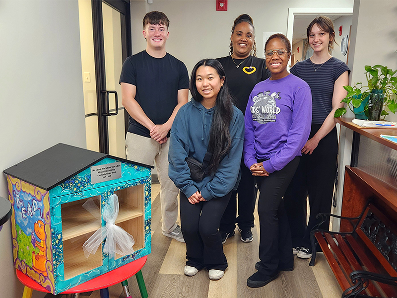 Five CSB members pose for the camera as they drop off the Little Library.