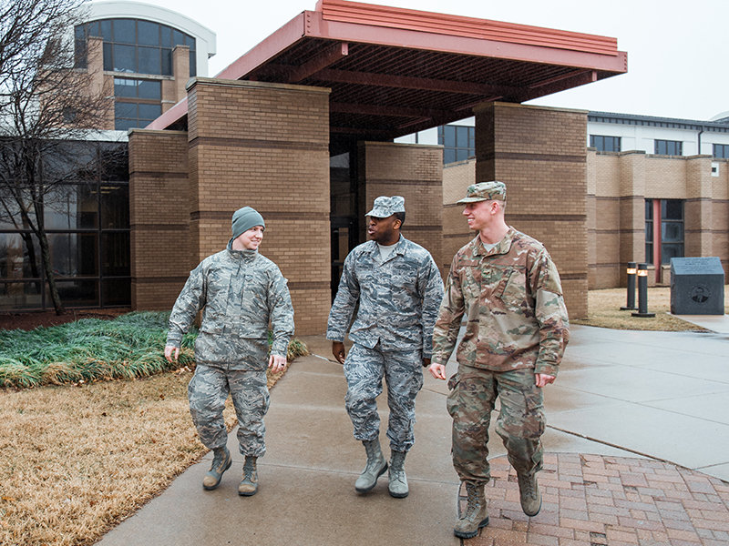 Three uniformed servicemembers walk outside at McConnell Air Force Base.